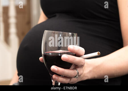 Pregnant woman holding a cigarette et verre de vin Banque D'Images