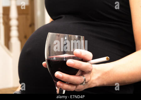 Pregnant woman holding a cigarette et verre de vin Banque D'Images