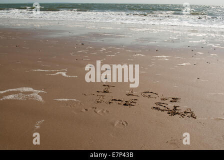'J'aime la mer" s'écrit dans le sable humide avec mer calme dans l'arrière-plan Banque D'Images