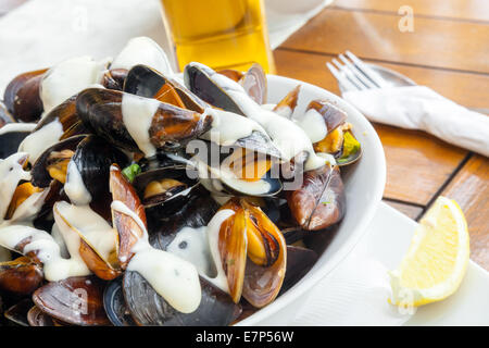 Assiette pleine de moules avec une sauce à l'ail sur la table in restaurant Banque D'Images