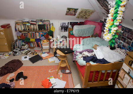 Un adolescent's messy chambre avec des vêtements, des livres et des biens abandonnés sur le sol. Banque D'Images