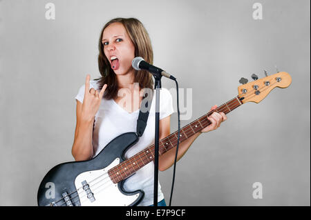 Fille avec la guitare basse et le microphone isolé sur fond gris Banque D'Images