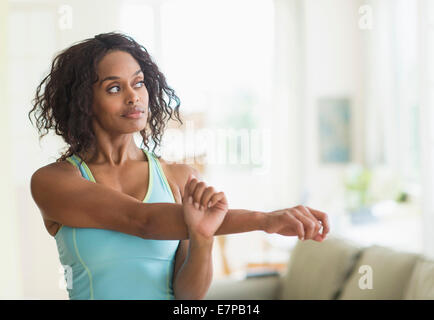 Woman stretching in living room Banque D'Images