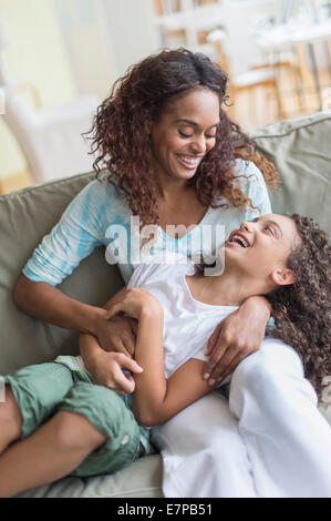 Mère fille tickling (8-9) sur canapé Banque D'Images