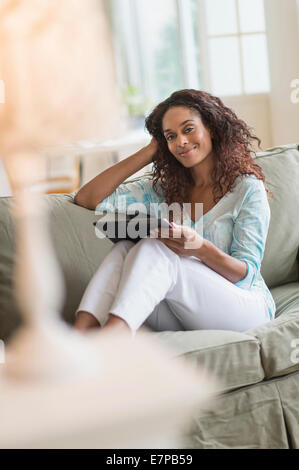 Woman using digital tablet on sofa Banque D'Images