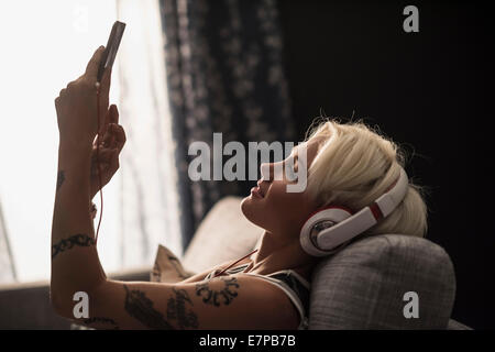 Woman lying on sofa using digital tablet Banque D'Images