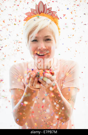 Woman wearing tiara blowing confetti Banque D'Images