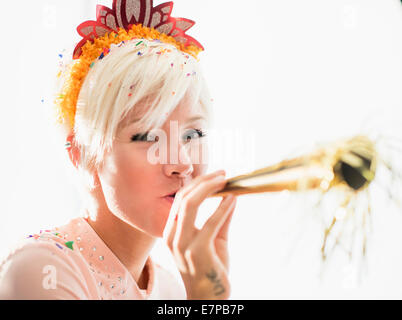 Woman wearing tiara soufflant soufflante party horn Banque D'Images