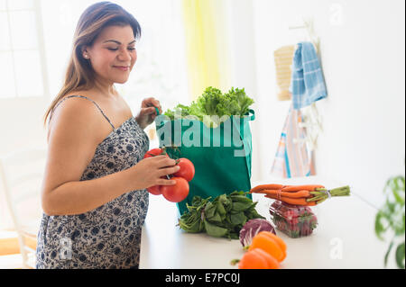 Femme sortant du sac à provisions de légumes Banque D'Images