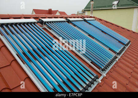 Collecteurs à vide- chauffe-eau solaire sur le toit de la maison rouge. Banque D'Images