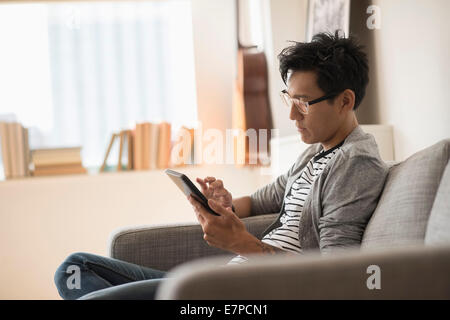 Homme assis sur un canapé et à l'aide de tablet Banque D'Images