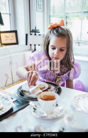 Girl (4-5) eating cookies à table à manger Banque D'Images