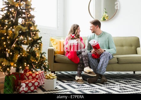 Jeune couple avec des bas de Noël sur canapé Banque D'Images