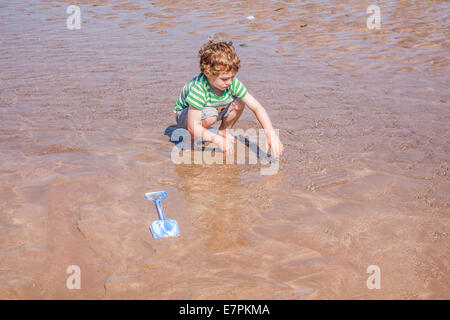 À l'âge de cinq ans, garçon jouant dans l'eau à Hope Cove, South Devon, Angleterre, Royaume-Uni. Banque D'Images