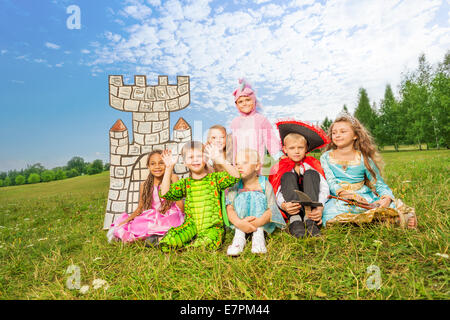 Les enfants en costumes du festival s'asseoir sur l'herbe Banque D'Images