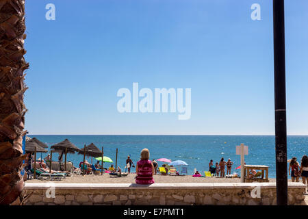 Une femme assise sur un mur à regarder le soleil sur la plage de Fuengirola, Costa del Sol, Málaga, Andalousie, Espagne, Europe Banque D'Images