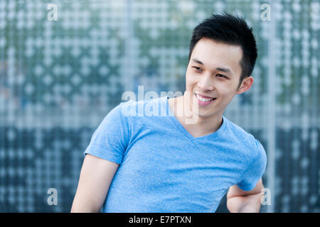 Portrait of young asian man smiling in urban environment with copy space Banque D'Images