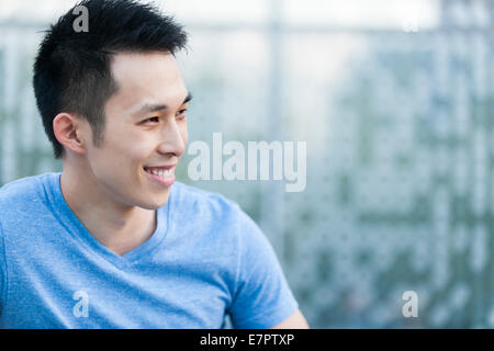 Portrait of young asian man in profile smiling on blue background with copy space Banque D'Images