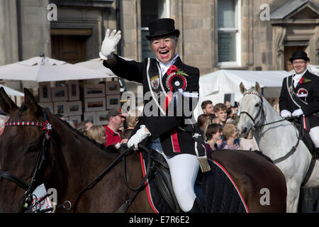 Une femme sur un cheval en agitant de gens dans la foule sur le Royal Mile, Édimbourg avant l'équitation annuelle des Marches cérémonie. Banque D'Images