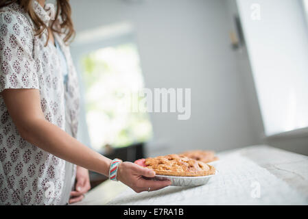 Une femme portant la nourriture à une table, se préparer pour un repas en famille. Banque D'Images