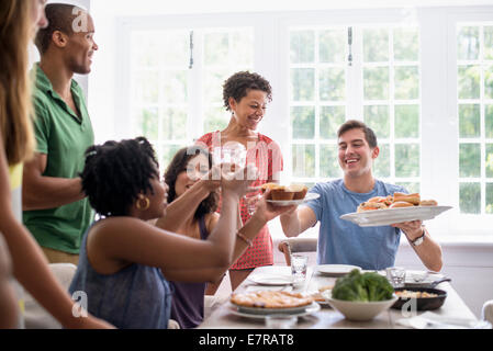 Une réunion de famille, hommes, femmes et enfants autour d'une table à manger partager un repas. Banque D'Images