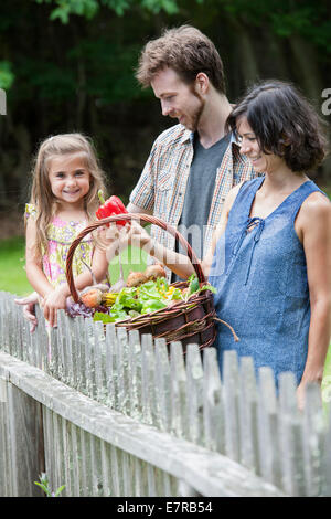 Comité permanent de la famille dans un jardin avec un panier de légumes. Banque D'Images