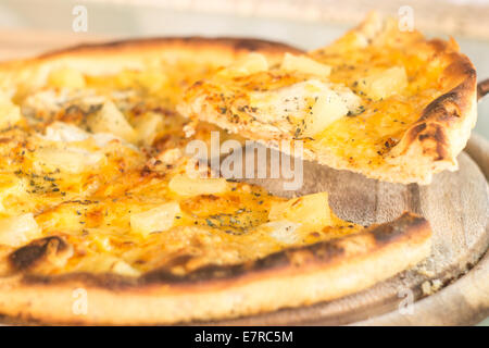 Coupe pizza cuite au four à l'ananas et la viande sur planche de bois. Selective focus image. L'heure des repas de restauration rapide Banque D'Images