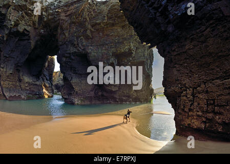 L'Espagne, la Galice, Ribadeo, Cathédrale s beach, plage, chien, marée basse, les rochers, rock arcs, célèbre, impressionnant, énorme rocher, falaises côtières, la côte, la baie, le sable, l'eau, des roches de schiste, Voyage, tourisme, nature, géologie, top 10 des plages en Espagne Banque D'Images