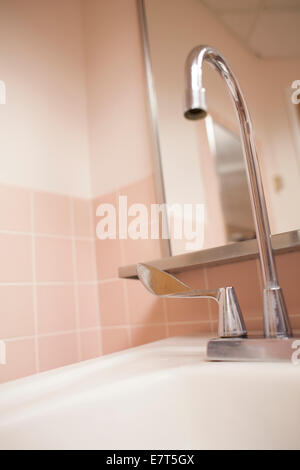 Lavabo dans une salle de bains, sol carrelé rose dans un hôpital public. Banque D'Images