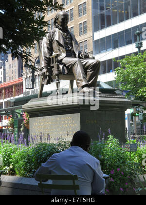 Statue d'Horace Greeley un jour d'été dans la région de Greeley Square, New York City. Tables et chaises entourent la statue. Banque D'Images