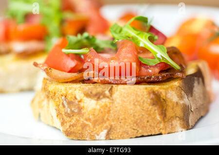 Sandwich Bruschetta fraîche au bacon, tomates et roquette Banque D'Images