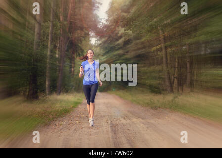 Athletic femme sur le jogging dans une forêt près de la caméra le long d'un chemin à travers les arbres dans un conce santé et fitness Banque D'Images