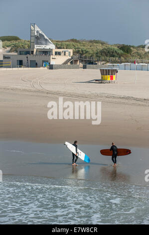 Deux surfeurs de quitter l'eau et de marcher jusqu'à l'O'Neill beach club le long de la mer du Nord à Blankenberge, Belgique Banque D'Images
