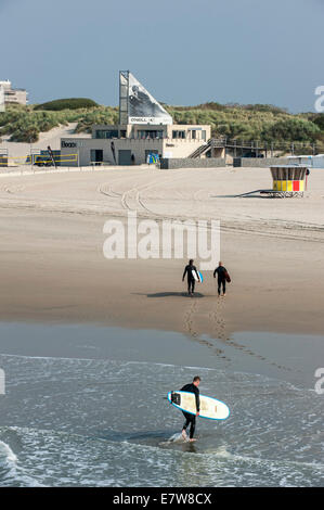 Trois surfeurs de quitter l'eau et de marcher jusqu'à l'O'Neill beach club le long de la mer du Nord à Blankenberge, Belgique Banque D'Images