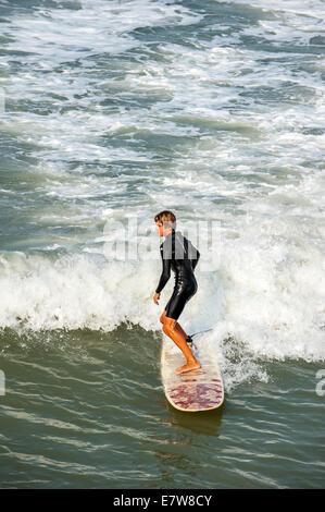 Les jeunes internautes en équitation wetsuit surf sur vague comme il se brise en mer Banque D'Images