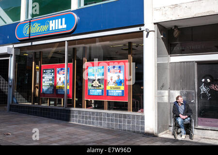 Homme handicapé dans un fauteuil roulant William Hill de livres à Sheffield South Yorkshire, UK Banque D'Images