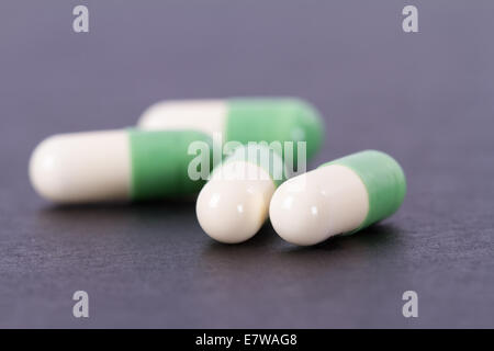 Capsules médicales vert et blanc sur noir table en bois. Banque D'Images