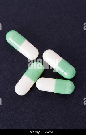 Capsules médicales vert et blanc sur noir table en bois. Banque D'Images