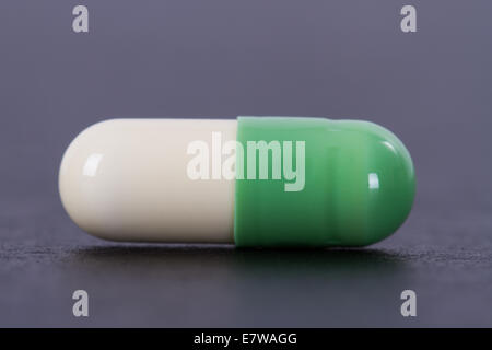 Capsules médicales vert et blanc sur noir table en bois. Banque D'Images