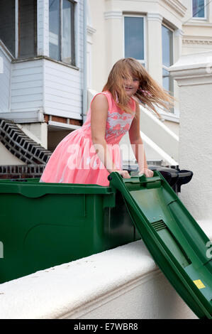 Happy smiling young girl playing dans un bac de recyclage Banque D'Images