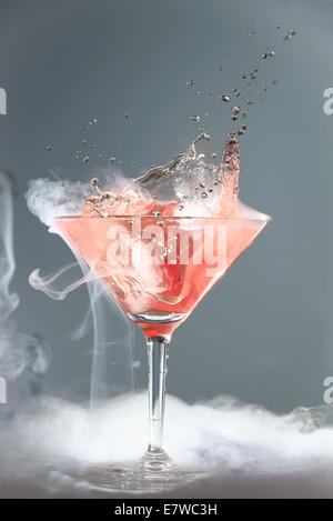 Fumeurs martini cocktail dans un verre conique avec vapeur wafting ou projection de gouttelettes d'une chute spectaculaire de la cerise effe