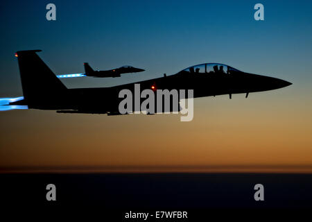 US Air Force F-15E Strike Eagle se profilent d'avions de chasse par le coucher de soleil qu'ils survolent l'espace aérien iraquien après avoir terminé sorties de combat contre des cibles d'ISIS en Syrie le 23 septembre 2014. L'achevé leur première missions de combat au-dessus de la Syrie s'attaque à des cibles d'ISIS. Banque D'Images
