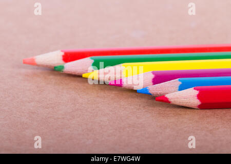 Crayons de couleur dans une rangée sur fond texturé. Banque D'Images