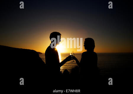 La silhouette d'un couple having drinks au coucher du soleil sur la falaise, Snug Cove, l'île kangourou en Australie Banque D'Images