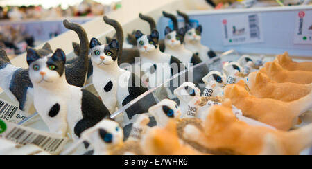 Rangées de figurines chat jouet sont alignés sur une étagère dans un magasin de jouets. Le noir et blanc et orange les chats. Banque D'Images