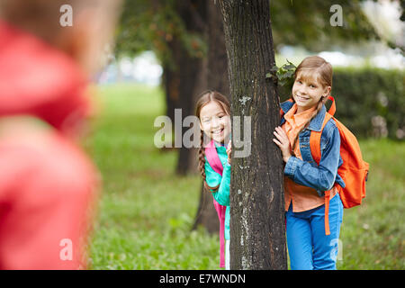 Cute écolières dans permanent occasionnel par un arbre dans le parc Banque D'Images