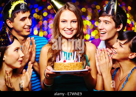 Belle jeune femme avec gâteau d'anniversaire, ses amis applaudir Banque D'Images