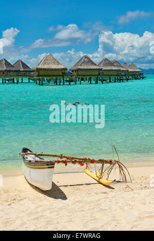 Bateau outrigger décorée en face de bungalows sur pilotis, Bora Bora, Polynésie Française Banque D'Images