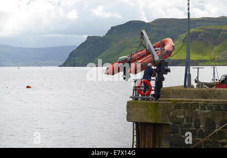 Un homme de la descente d'une petite embarcation gonflable à Portree Harbour sur l'île de Skye, en Écosse, les Highlands écossais. Banque D'Images