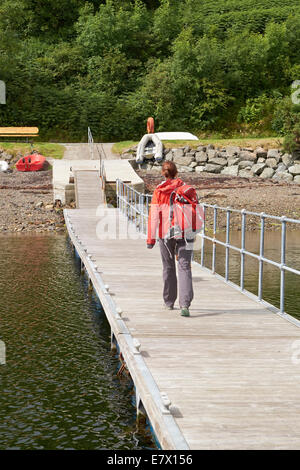 Une femme débarquant après un voyage en bateau sur l'île de Skye, en Ecosse. Banque D'Images